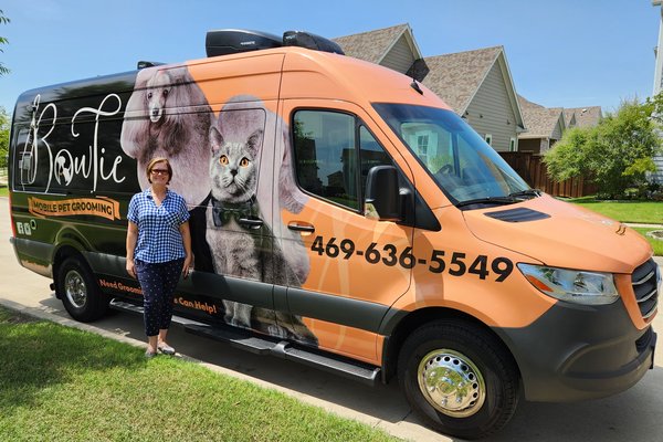 Helen from Bow Tie standing next to the branded orange mobile grooming van